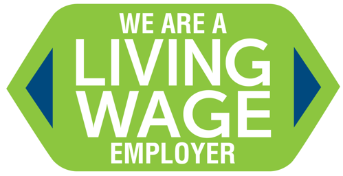 Green badge-shaped graphic with blue arrows on each side and white text reading 'We Are a Living Wage Employer.'